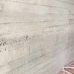 Weg te werken grindnesten in een betonwand met plankenstructuur - esthetische betonherstelling
