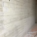 Weggewerkte grindnesten in een betonwand met plankenstructuur